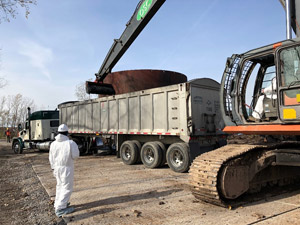 November 2019 - Site 108 - view looking west. Long stick excavator fitted with a smooth blade for loading stabilized tar into tractor trailers; Tank 2 is visible in the background.