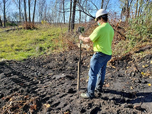 November 2020 - A survey contractor surveying the location and elevation of one end of a test pit